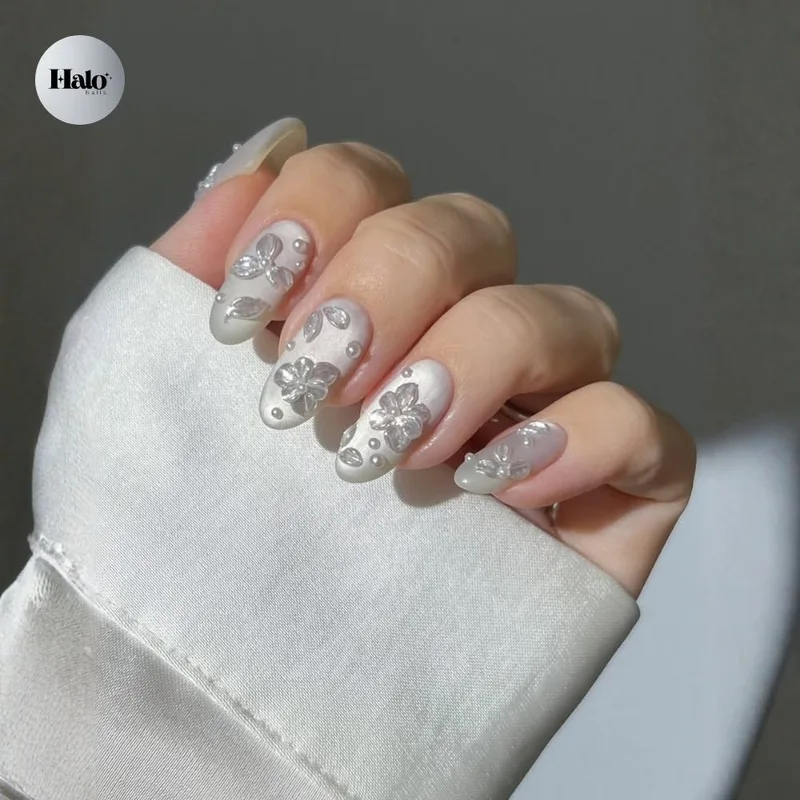 Pearl white nails with delicate 3D floral art, soft as porcelain.