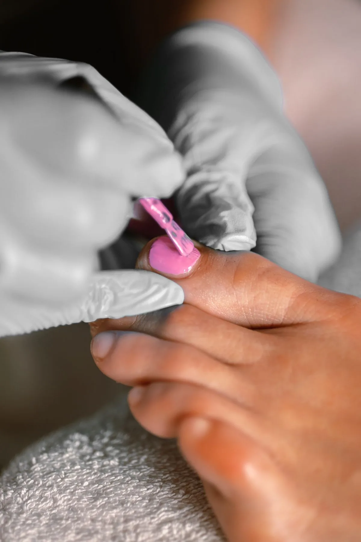 A pedicure in progress, pink polish being laid over a fresh spa pedicure.